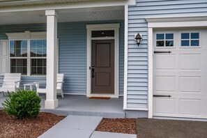 A house with a porch, a front door, and a garage door. - Five Bedroom Home with Great Amenities in West OC (Berlin)