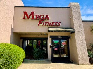 En bygning med et skilt, der viser "Mega Fitness" og nummer 9676.
