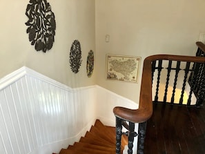 A wooden staircase with a white baseboard and a dark wooden handrail. - Victorian 2 bedroom sleeps six by Forsyth Park (Savannah)