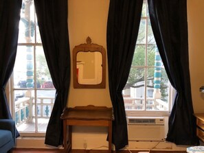 A room with a large window, a mirror on the wall, and a small wooden table. - Victorian 2 bedroom sleeps six by Forsyth Park (Savannah)