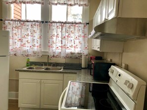 A compact kitchen with a sink, stove, and cabinets. - Victorian 2 bedroom sleeps six by Forsyth Park (Savannah)