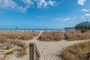 A beach path leading to a wooden structure, a pier extending into the water, and a clear sky. - Beachfront Studio Retreat with Resort Amenities at Yachtsman S1104 (Myrtle Beach)