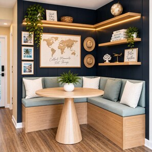 A corner seating area with a round wooden table, a globe, and framed travel-themed items on shelves. - Beachfront Studio Retreat with Resort Amenities at Yachtsman S1104 (Myrtle Beach)