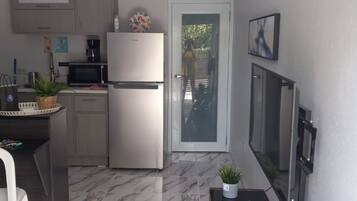 A compact kitchen with a refrigerator, microwave, and a small dining area.