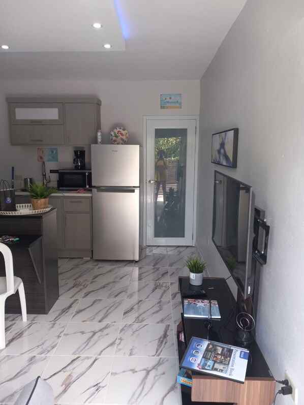 A compact kitchen with a refrigerator, microwave, and a small dining area.