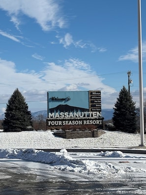 Ein Schild empfängt Besucher im Massanutten Four Season Resort und bewirbt Annehmlichkeiten wie Golfplätze, Spa und Schneesportmöglichkeiten.