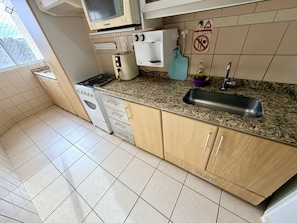 A kitchen with a stove, microwave, sink, and cabinets. - CRCN - Vitoria das Thermas (Caldas Novas)