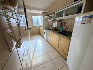 A kitchen with a microwave, stove, sink, and cabinets. - CRCN - Vitoria das Thermas (Caldas Novas)