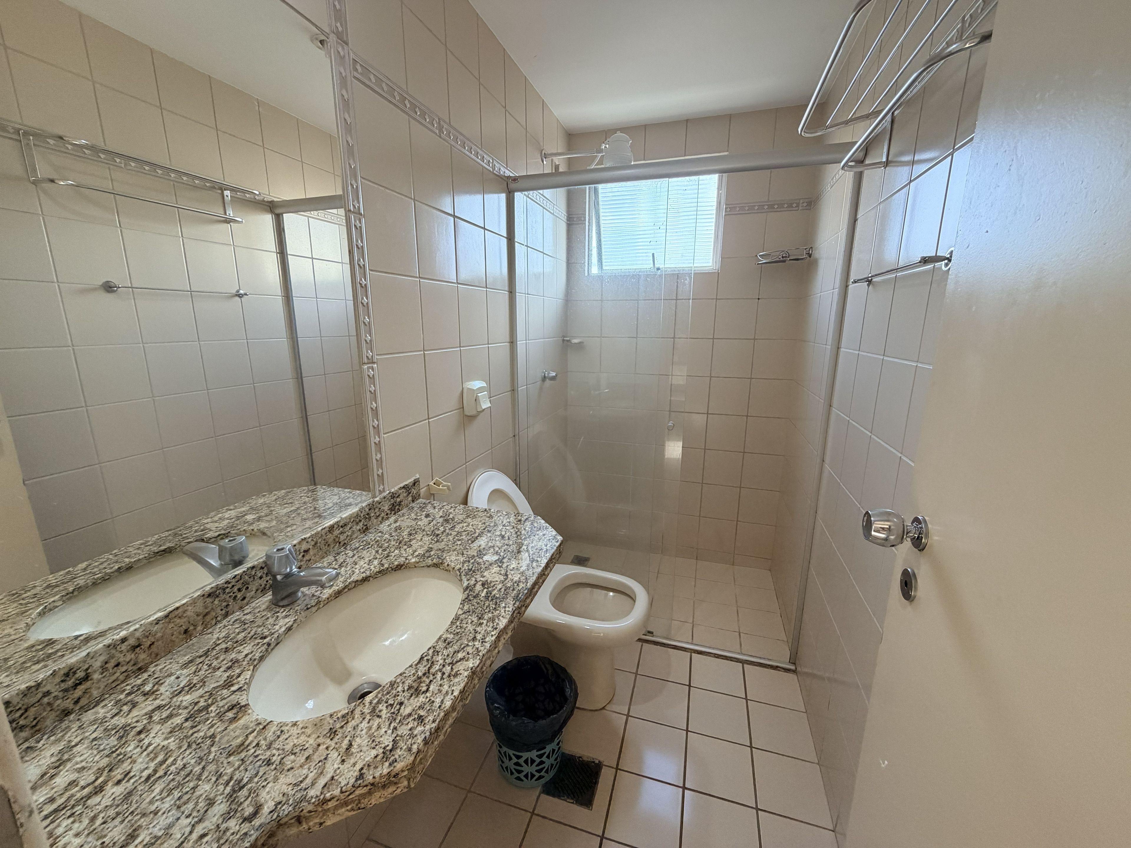 Un baño con lavamanos de granito, inodoro y cabina de ducha.