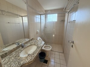 A bathroom with a granite sink, a toilet, and a shower stall. - CRCN - Vitoria das Thermas (Caldas Novas)