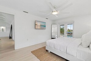 A bedroom with a bed, a ceiling fan, a painting, and a view of a pool through a glass door. - Point of View - Sanibel Island House with Private Pool, Lake Views & Beach Access! (Sanibel)