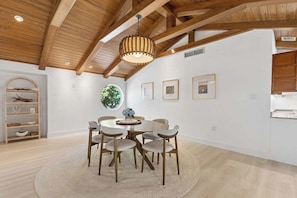 A dining area with a round table, six chairs, a wooden ceiling, and a hanging light fixture. - Point of View - Sanibel Island House with Private Pool, Lake Views & Beach Access! (Sanibel)