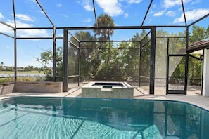 A swimming pool with a glass enclosure, surrounded by trees and a clear sky. - Point of View - Sanibel Island House with Private Pool, Lake Views & Beach Access! (Sanibel)