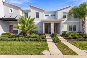 A modern two-story residential building with a red door, a covered porch, and a well-maintained front yard with grass and shrubs. - Magical Getaway with Private Pool, Top location (Davenport)