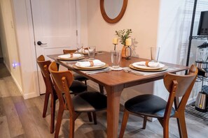 A dining area with a wooden table set for four, surrounded by chairs with cushioned seats. - 2 Bedroom / Full Kitchen (Grandview)