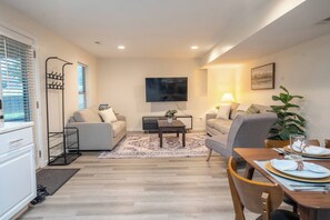 A modern living room with a sofa, coffee table, and dining table set up. - 2 Bedroom / Full Kitchen (Grandview)
