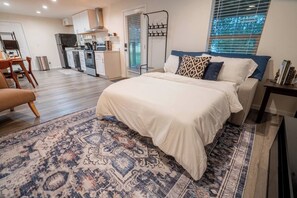 Une chambre à coucher avec un grand lit, un tapis à motifs, une table de chevet et une fenêtre avec des stores.