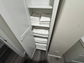 Un placard de rangement avec des étagères où sont pliées des serviettes blanches.