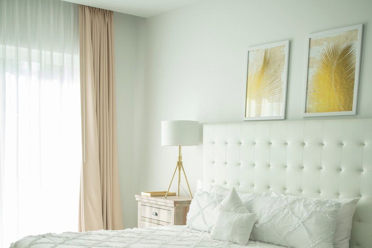 A bedroom with a large bed, a bedside table, a lamp, and two wall art pieces.