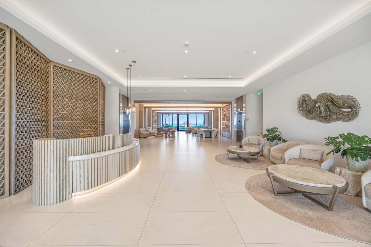 A spacious lobby with a reception desk, seating area, and a large window offering a view.