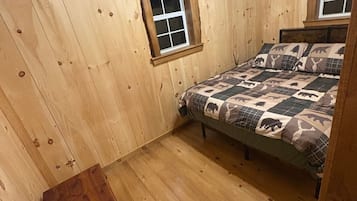 Une pièce aux murs en bois et un lit recouvert d’une couvre-lit à motifs.