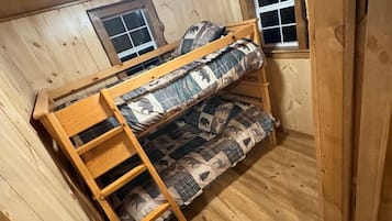 Un lit superposé avec une échelle, des murs en bois et une fenêtre.