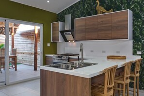 Une cuisine moderne dotée d’un îlot central, d’un évier en acier inoxydable et de meubles de rangement en bois.