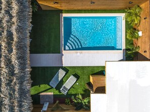 Ein Pool auf dem Dach mit zwei Liegestühlen und einer Holzterrasse.
