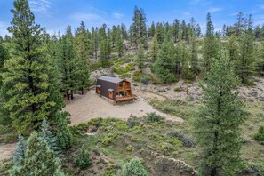 A cabin surrounded by dense forest, with a gravel driveway leading to a wooden deck. - Ponderosa Pines Cabin Retreat (Duck Creek Village)