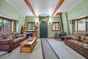 Ein gemütliches Wohnzimmer mit Kamin, zwei Sofas, einem Couchtisch und einem großen Fenster.