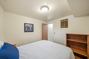 A bedroom with a bed, a door, a wall-mounted shelf, and a ceiling light. - Ponderosa Pines Cabin Retreat (Duck Creek Village)