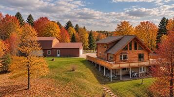 A wooden cabin with a deck, surrounded by autumn foliage.