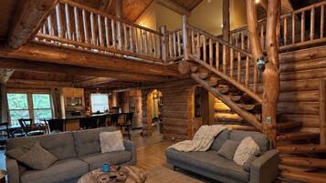 Ein großzügiger Wohnbereich mit einer Holztreppe, zwei Sofas, einem Couchtisch und einem Deckenventilator.
