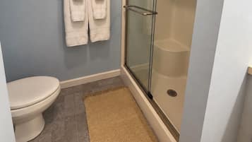 Ein Badezimmer mit Toilette, einer Duschkabine aus Glas und einem Handtuchhalter mit zwei Handtüchern.