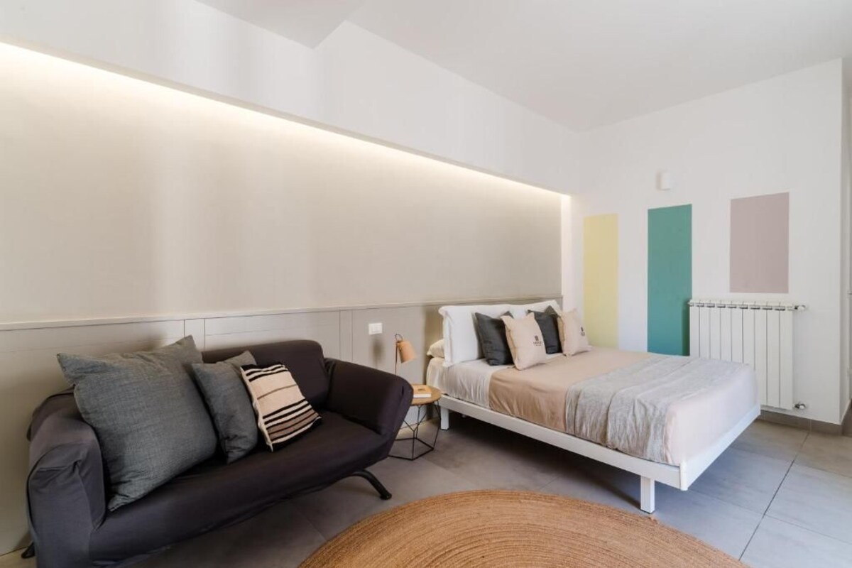Un dormitorio moderno con una cama, un sofá y una mesita de noche.