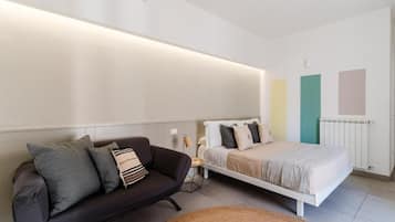 Quarto moderno com cama, sofá e mesa de cabeceira.