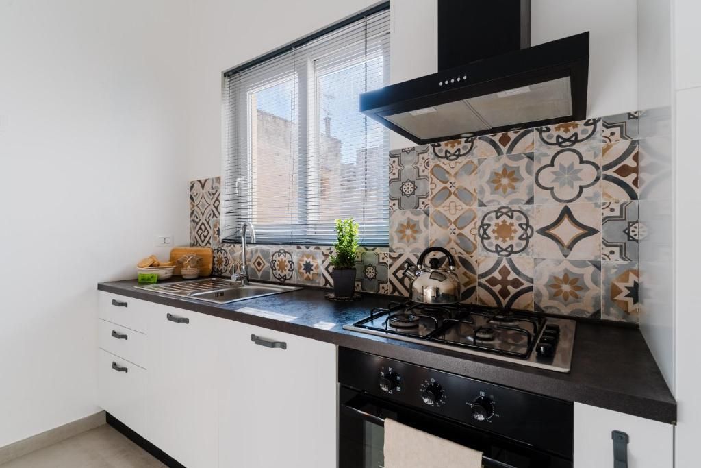 Una cocina con estufa a gas, horno y ventana con persianas.