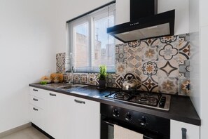 Una cocina con estufa a gas, horno y ventana con persianas.