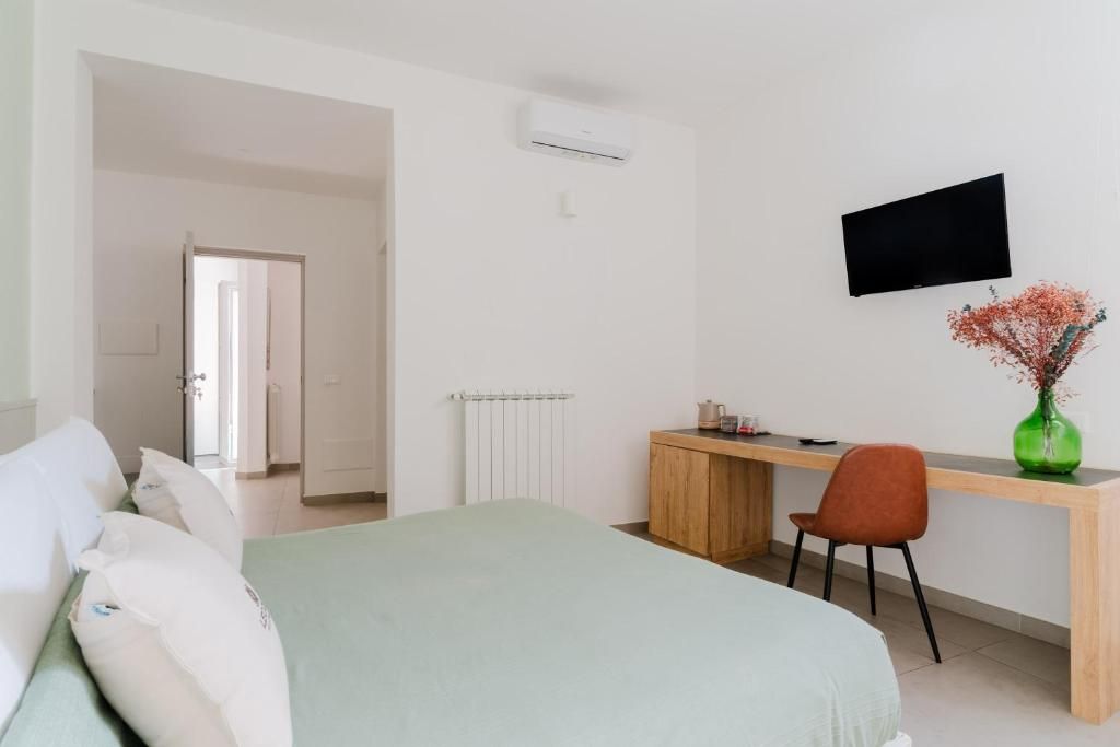Un dormitorio con cama, escritorio, silla, televisor y radiador.