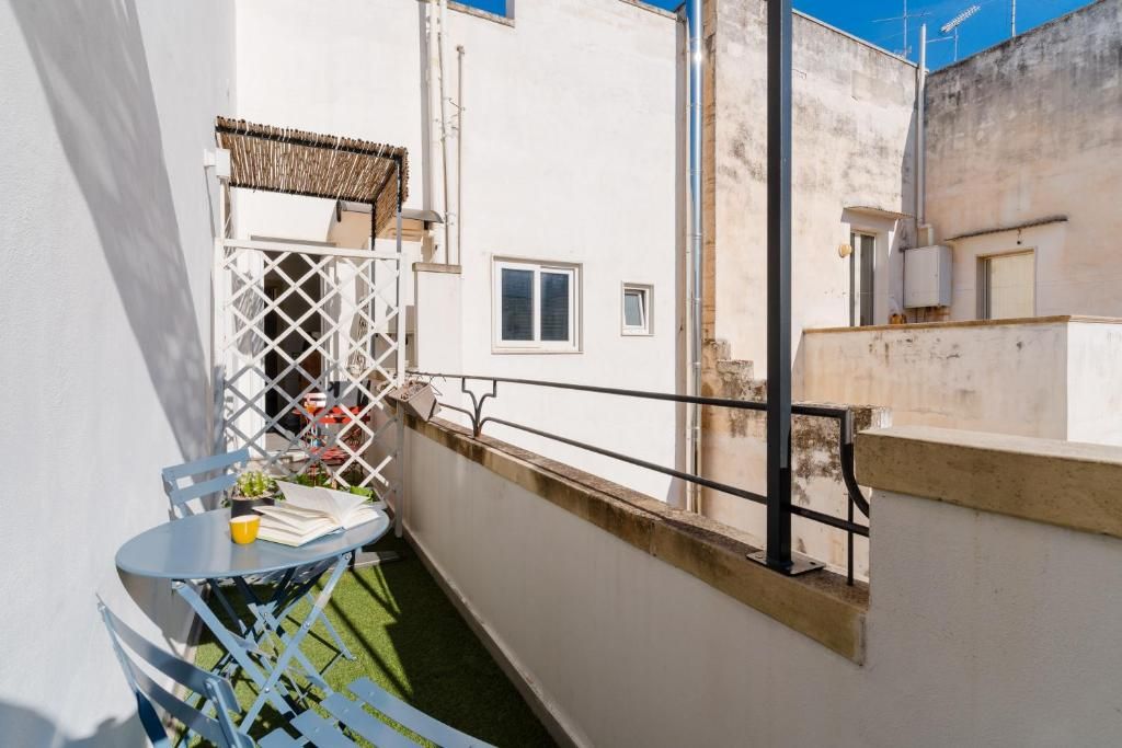 Un'area salotto esterna con un tavolo e sedie, un muro bianco e una finestra.