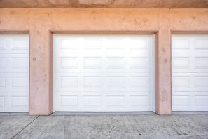 Un garage con tre porte basculanti bianche e un pavimento in cemento.