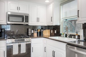 A modern kitchen with white cabinetry, a stainless steel range, a microwave, and a dishwasher. - Mermaid Cove With Beach Days & Hot Tub Nights! AC, Ocean, Pool/HotTub (Oceanside)