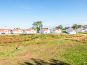 A row of white houses with red roofs, a clear sky, and a grassy field in the foreground. - 4 Star Holiday Home in Laeso (Læsø)