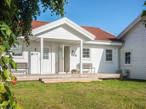 A white two-story house with a covered porch, a red-tiled roof, and a small front yard. - 4 Star Holiday Home in Laeso (Læsø)