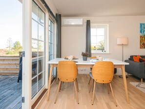A dining area with a table and chairs, a window with curtains, a sofa, and a lamp. - 4 Star Holiday Home in Laeso (Læsø)