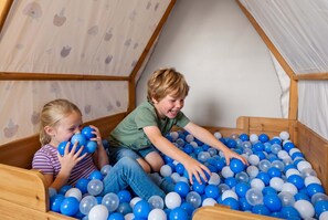 Two children playing in a wooden ball pit with a sloped ceiling. - Helen Haus: Golf Sim & Hot Tub Theater Retreat (Helen)