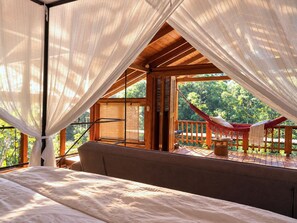 A bedroom with a bed, a wooden ceiling, and a view of a hammock outside. - Kubla Khan - Chirripó riverfront mountain retreat (Perez Zeledon)