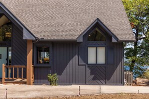 A modern house with a dark grey exterior, a prominent gable roof, and a small porch with wooden railings. - Ridgeview Lodge at Beaver Lake (Garfield)