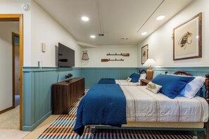 A bedroom with a bed, bedside tables, a television, and wall-mounted decorations. - Ridgeview Lodge at Beaver Lake (Garfield)