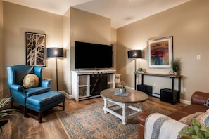 A living room with a blue armchair, a television, a coffee table, and a patterned rug. - 3 Queen BR Home Near Grandview Ave & Inclines (Pittsburgh)